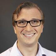 Smiling white male wearing glasses and a light striped button-down shirt.