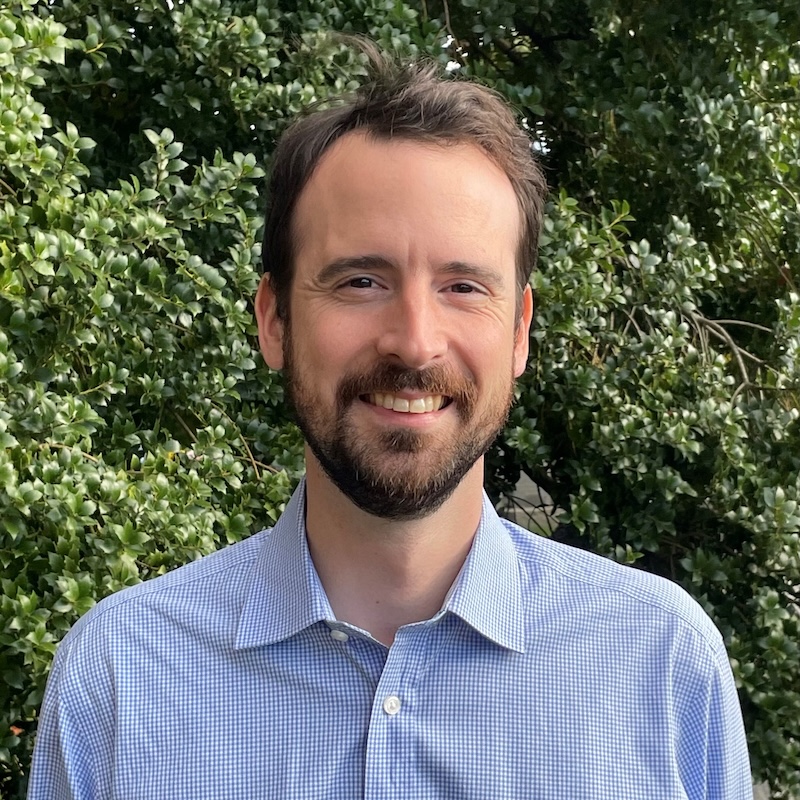 Smiling man with short hair and beard in a blue shirt.