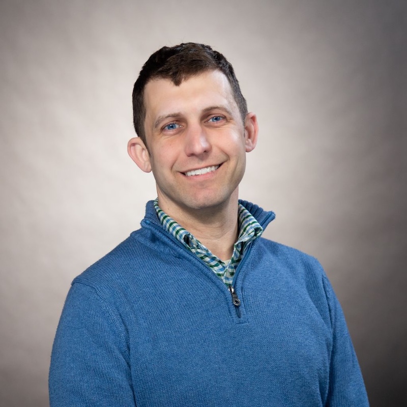Gregory Wiedeman, a white man with brown hair and a blue shirt with a grey background.