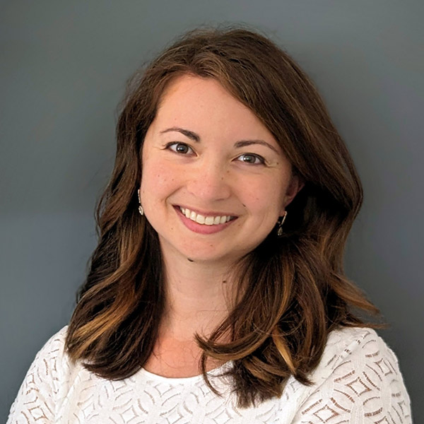 Brown-haired woman who is half Asian, half white and who has a welcoming smile