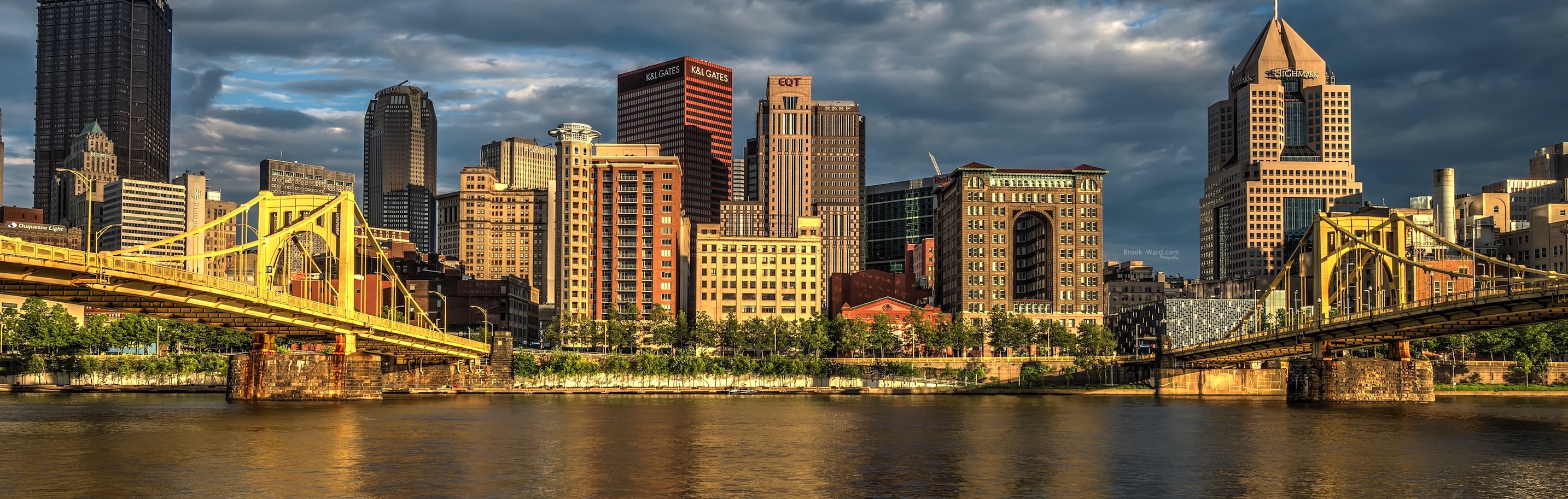 Daytime photo of Pittsburgh downtown area with gray clouds framed by yellow bridges